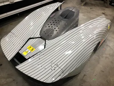 Overhead silver pinstripe-wrapped McLaren Speedtail body panels on workshop floor
