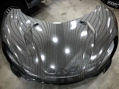 Symmetrical front hood of grey pinstripe-wrapped McLaren Speedtail in workshop