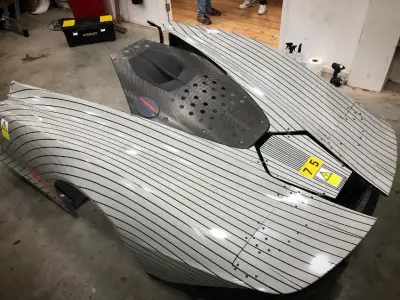 Overhead silver pinstripe-wrapped McLaren Speedtail body sections in workshop