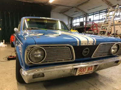 Blue Plymouth Barracuda race car front with white stripes and 900-WA plate in workshop