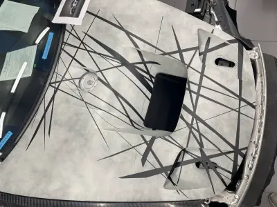 Grey Porsche 935 bonnet with black abstract line graphics being applied, carbon vent detail
