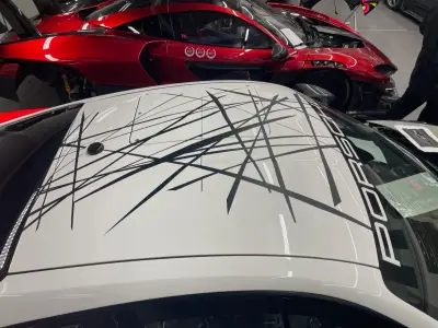 White Porsche 935 roof with black scratch-line livery, red McLaren behind
