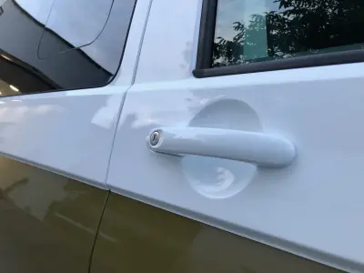 Close-up of white door handle on part-wrapped VW Transporter, gold lower panel