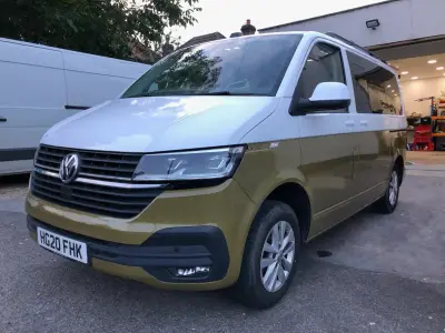 White-and-gold two-tone VW Transporter van, front driver-side angle