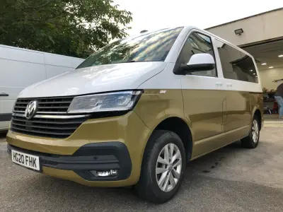 Two-tone white-over-gold VW Transporter van at signage workshop, low front angle