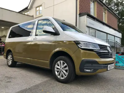 White-and-gold two-tone VW Transporter van, full front-left view, plate HG20 FHK