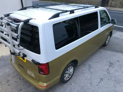 Rear-right of a two-tone white-over-olive VW Transporter van with bike rack