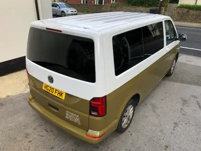 Rear of two-tone VW Transporter van with white house line-drawing graphic decal