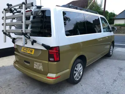 Rear driver-side of white-and-gold VW Transporter van with mounted bike rack