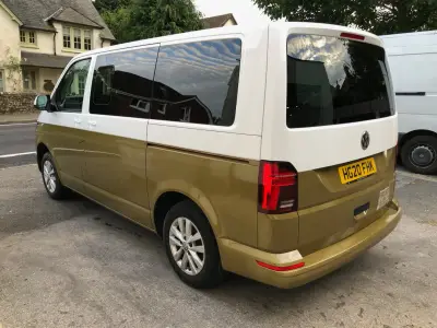 Rear three-quarter of white-and-gold VW Transporter van parked roadside