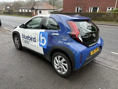 Blue and white Toyota Aygo X part wrap with Bluebird Care branding, rear view