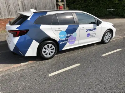 White Toyota Corolla estate with blue DISKING IT part wrap parked on a lane
