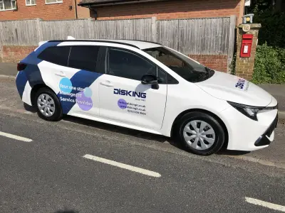 Toyota Corolla estate in white and blue DISKING part wrap, rear three-quarter view