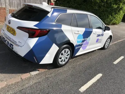 Rear of white Toyota Corolla estate with blue DISKING IT graphics and part wrap