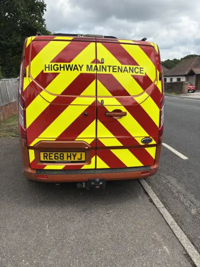 Rear of orange Ford Transit with red and yellow Highway Maintenance chevron graphics