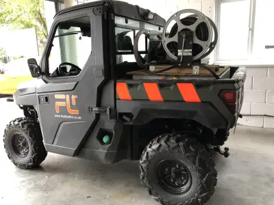 Grey Polaris Ranger UTV with orange First Line Fire markings and hose reel in bed