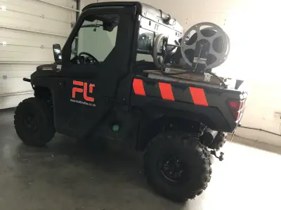 Black Polaris Ranger UTV with red First Line Fire FL graphics in a garage