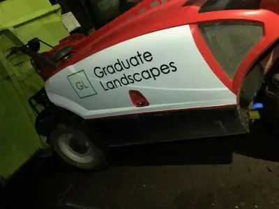 Green flail mower and red tractor with white Graduate Landscapes lettering