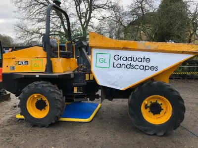 Yellow JCB 6T dumper with white Graduate Landscapes skip decal, side view