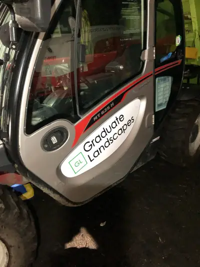 Graduate Landscapes magnetic door sign with green GL logo on a Manitou MT 625 telehandler cab