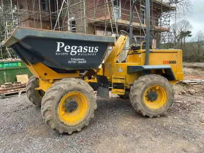 'Pegasus Builders' signwriting on the skip of a yellow site dumper at a housebuild