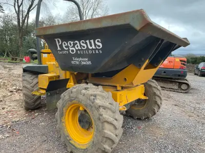 Yellow site dumper with white 'Pegasus Builders Est 1979' lettering on its dump skip