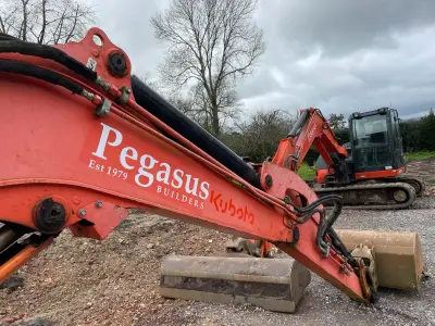 'Pegasus Builders' white decal along the orange boom of a Kubota excavator