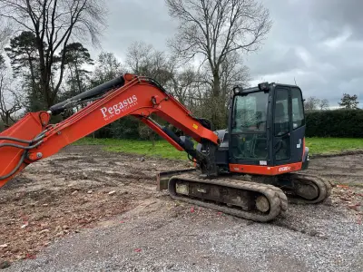 Orange Kubota KX080-4 excavator with 'Pegasus Builders' lettering along its boom