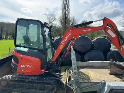 Kubota U27-4 mini excavator on a trailer with 'Pegasus Builders' lettering on the orange boom