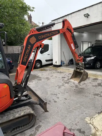 Orange Kubota excavator boom with black-and-orange 'Spectrum Construction' graphics