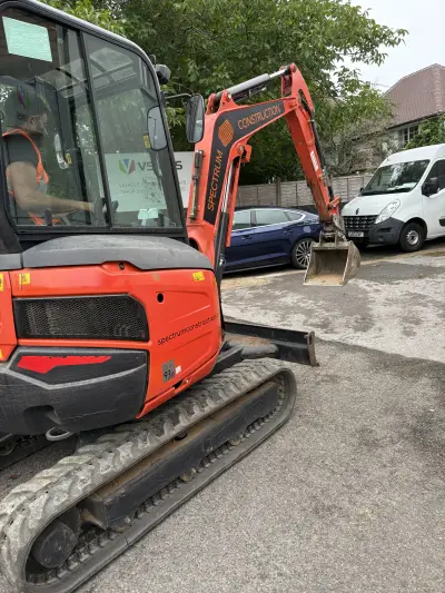 Orange Kubota excavator with 'Spectrum Construction' boom and web-address graphics in the VSigns yard