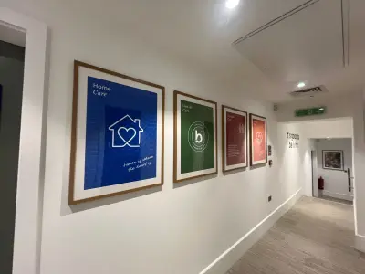Row of framed Bluebird Care service posters, Home Care and Live-in Care, along an office corridor
