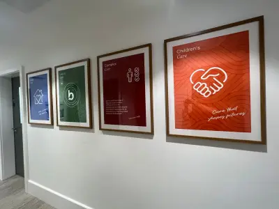 Four framed Bluebird Care posters including Children's Care along a white office corridor