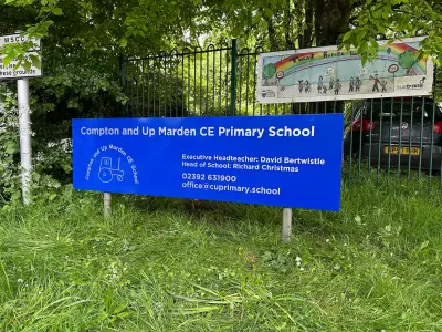 Blue 'Compton and Up Marden CE Primary School' sign with tractor logo and contact details