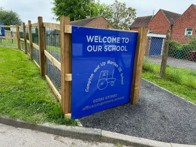 Angled view of the blue 'Welcome to Our School' Compton and Up Marden CE School sign