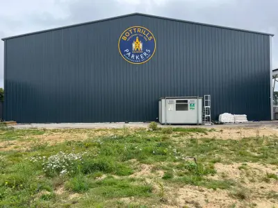 Large Bottrills Parkers roundel sign on a grey warehouse wall in Chichester