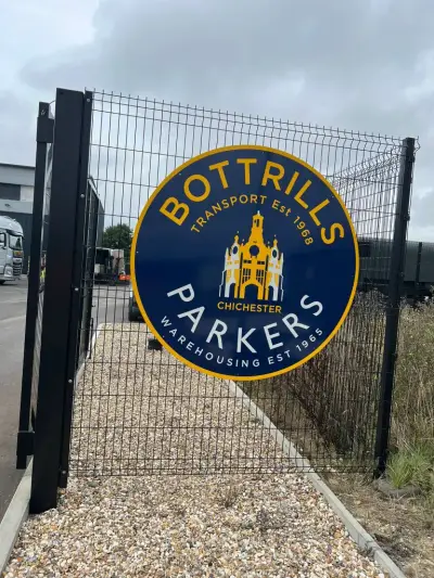 Bottrills Parkers circular navy and yellow sign fixed to a black mesh gate