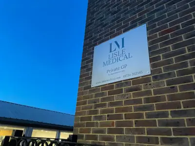 Lisle Medical Private GP white wall-mounted sign on a brick building at dusk