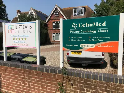 Just Ears Clinic and EchoMed post-mounted forecourt signs outside a brick house