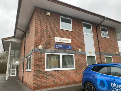 Bluebird Care blue fascia sign and window recruitment graphics on a brick shopfront