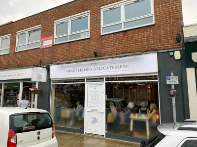 Madeleine's Delicatessen white shopfront fascia sign and matching projecting hanging sign