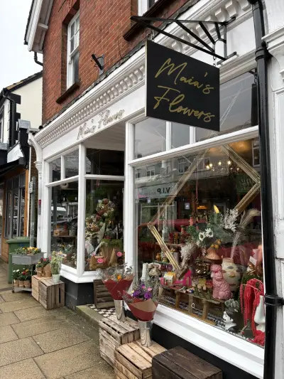 Maia's Flowers florist shopfront with gold signwriting and black projecting hanging sign