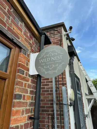 Wild Nest yoga and pilates grey circular projecting blade sign mounted on a brick wall