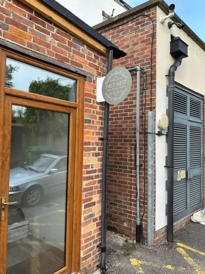 Wild Nest circular projecting sign on a brick building beside timber patio doors