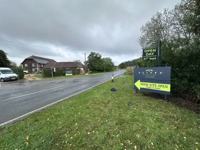 Alitex Glasshouses Site Entrance Ahead board on a grassy bank beside a field