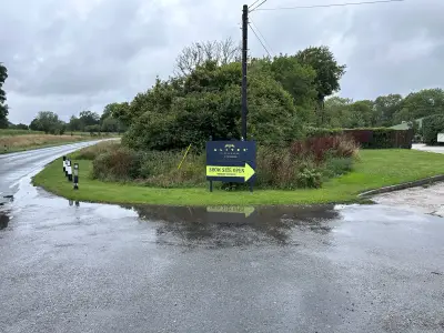 Alitex Glasshouses Show Site Open arrow board on a wet roadside island at a junction