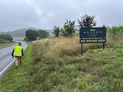 Alitex Glasshouses Site Entrance Ahead board with a worker in hi-vis walking the roadside