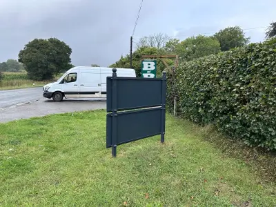 Rear of a newly installed grey Alitex site board with a green B and B sign behind