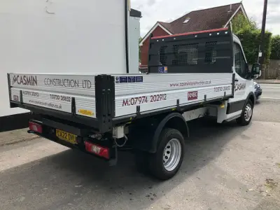 White Ford Transit dropside tipper with red Casmin Construction Ltd signwriting on the bed