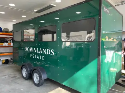 Dark green horsebox trailer with white Downlands Estate signwriting on the side